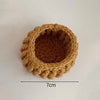 A round, hand-crocheted rose flower coaster in a warm brown color.