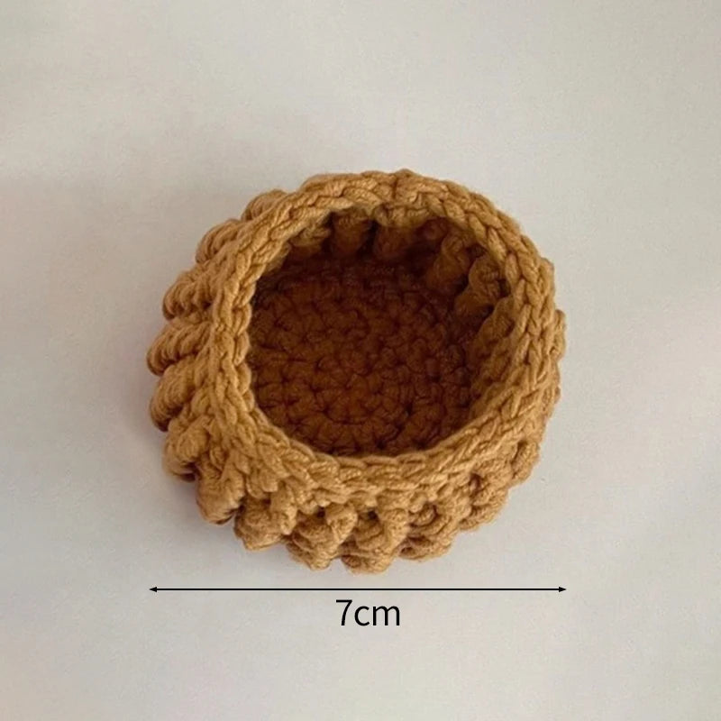 A round, hand-crocheted rose flower coaster in a warm brown color.