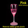 Tasse à boire en verre rose avec une pile à l'intérieur, faite de plastique alimentaire.