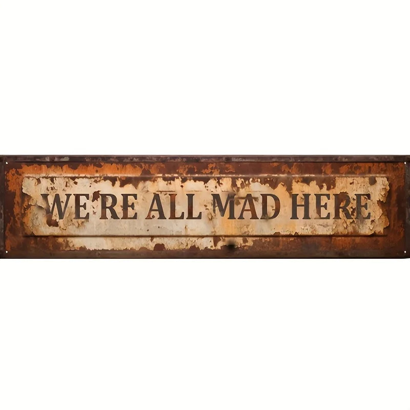 A weathered, rectangular vintage metal sign with distressed orange-brown patina and faded white text that reads We're all mad