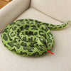 A realistic green and yellow patterned snake plush toy coiled on a light-colored surface.