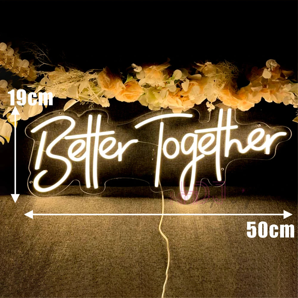 A glowing neon sign spelling Better Together is displayed against a dark background with floral decorations.
