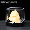 A yellow aventurine crystal specimen is displayed inside a clear box on a dark surface.