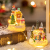 A glowing Christmas gingerbread house resin ornament set decorated with snow and festive lights.