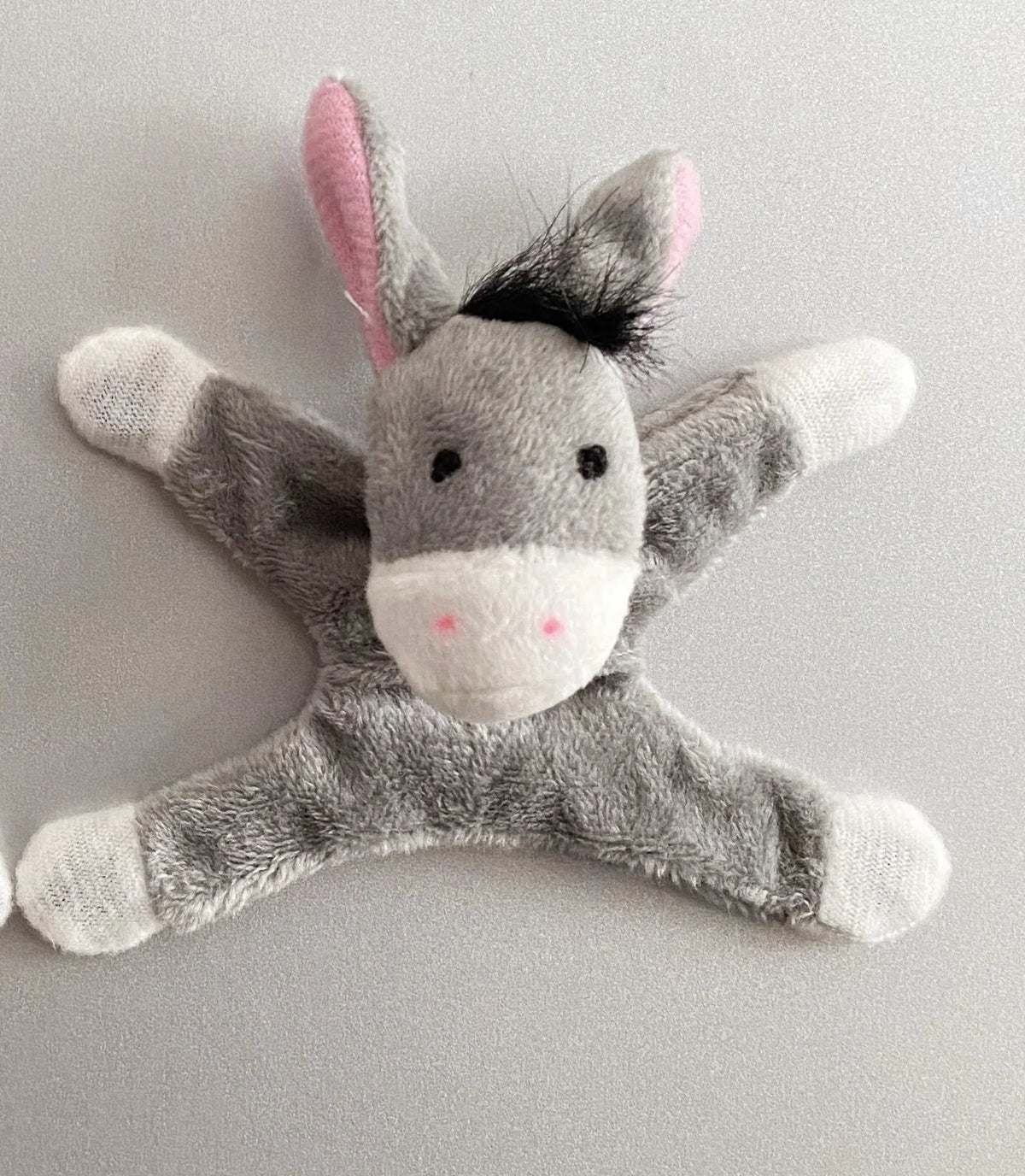 A gray plush animal figurine resembling a donkey or horse with pink ears and white accents.