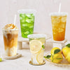 A collection of refreshing iced beverages in clear plastic cups, including lemonade and iced tea, displayed on a white surfac