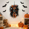 A black and orange Halloween BOO wreath with a pumpkin garland hanging on a white wall.