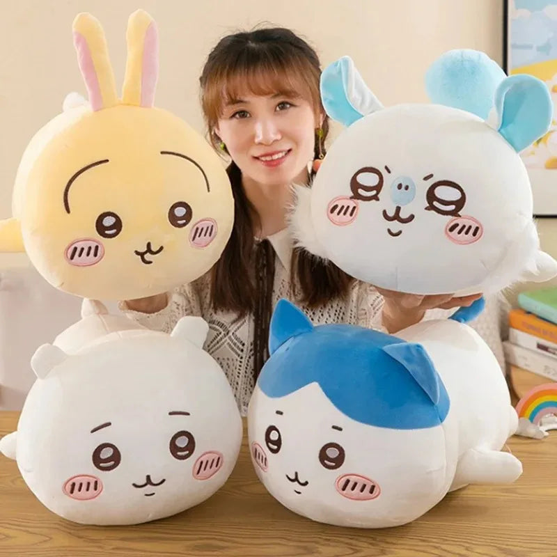 Three Chiikawa Hachiware plush pillows in yellow, white, and blue are displayed on a wooden surface.