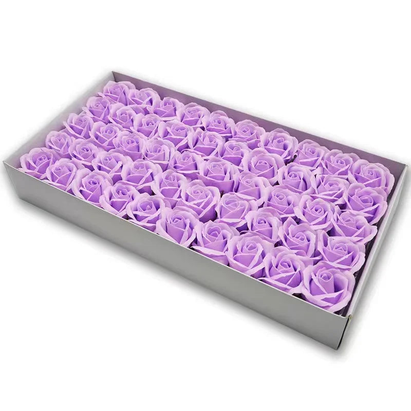 A rectangular box filled with numerous artificial purple rose flower heads for crafting and decoration.