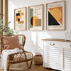 Three framed abstract geometric canvas prints featuring warm earth tones and black on a white wall.