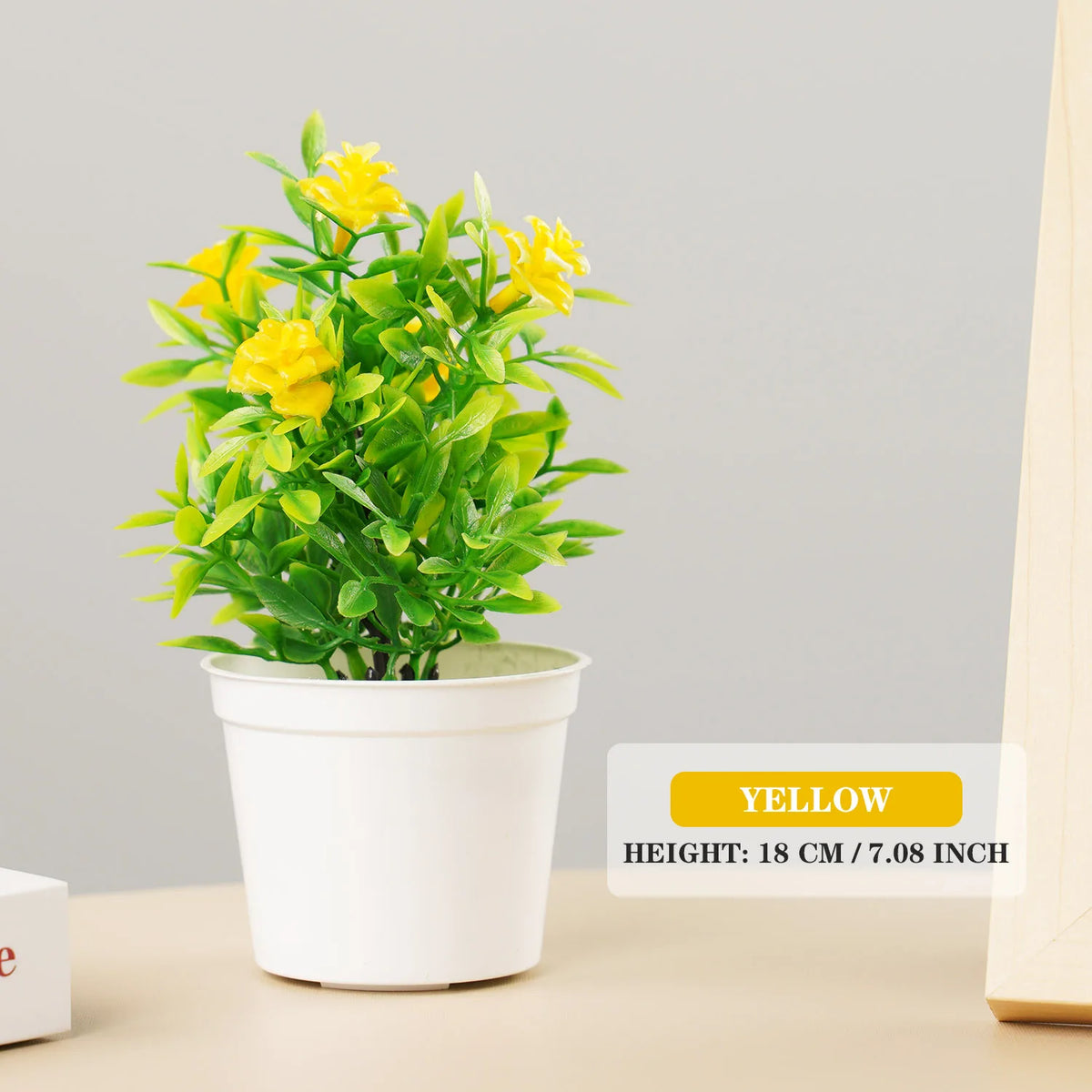 Artificial bonsai tree with bright yellow flowers in a white pot