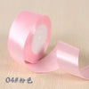 A roll of pink silk satin ribbon used for gift wrapping and craft projects.