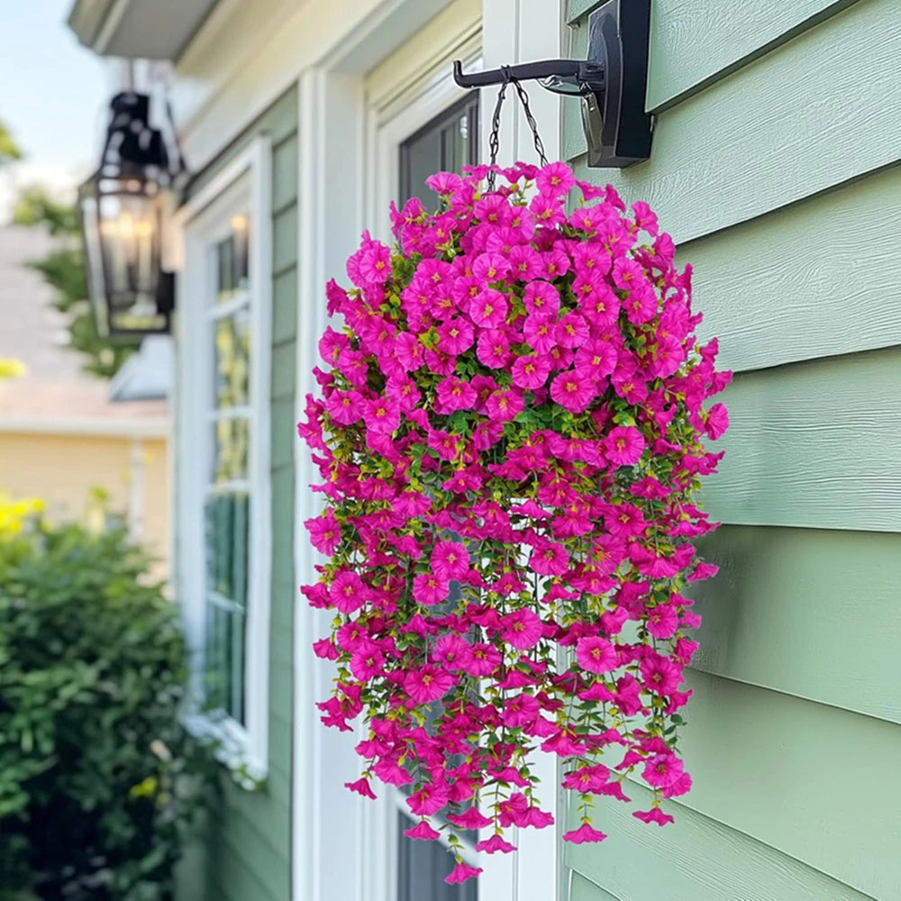 A vibrant pink artificial morning glory vine cascading down a light green siding wall.
