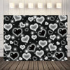 A dark backdrop covered with glowing white and black heart shapes, illuminated by overhead lights.