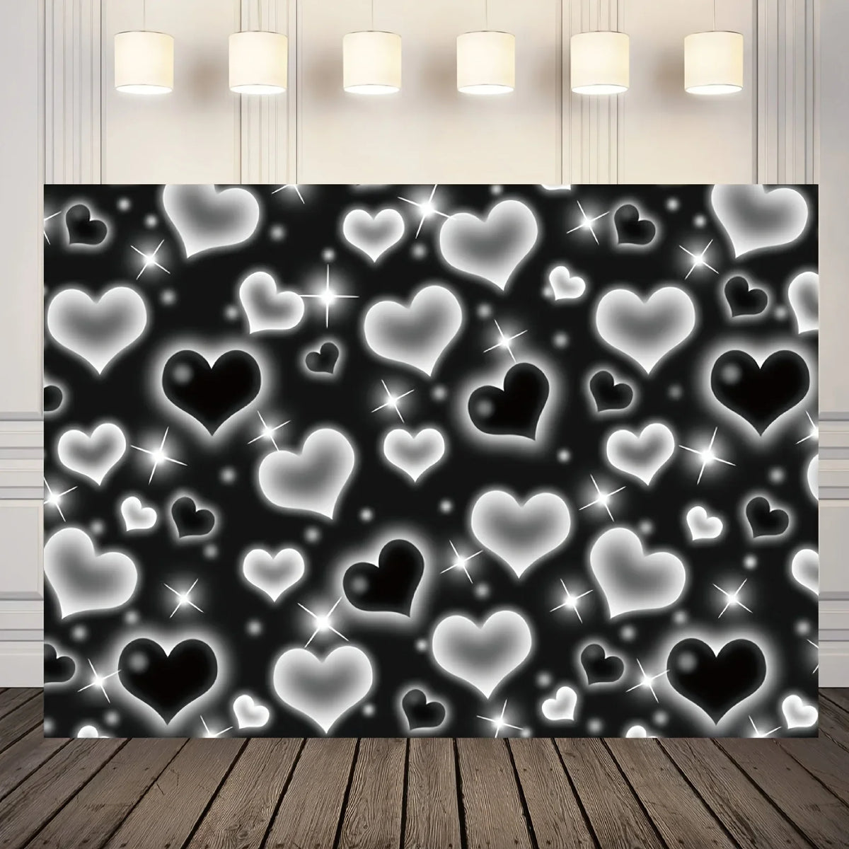 A dark backdrop covered with glowing white and black heart shapes, illuminated by overhead lights.