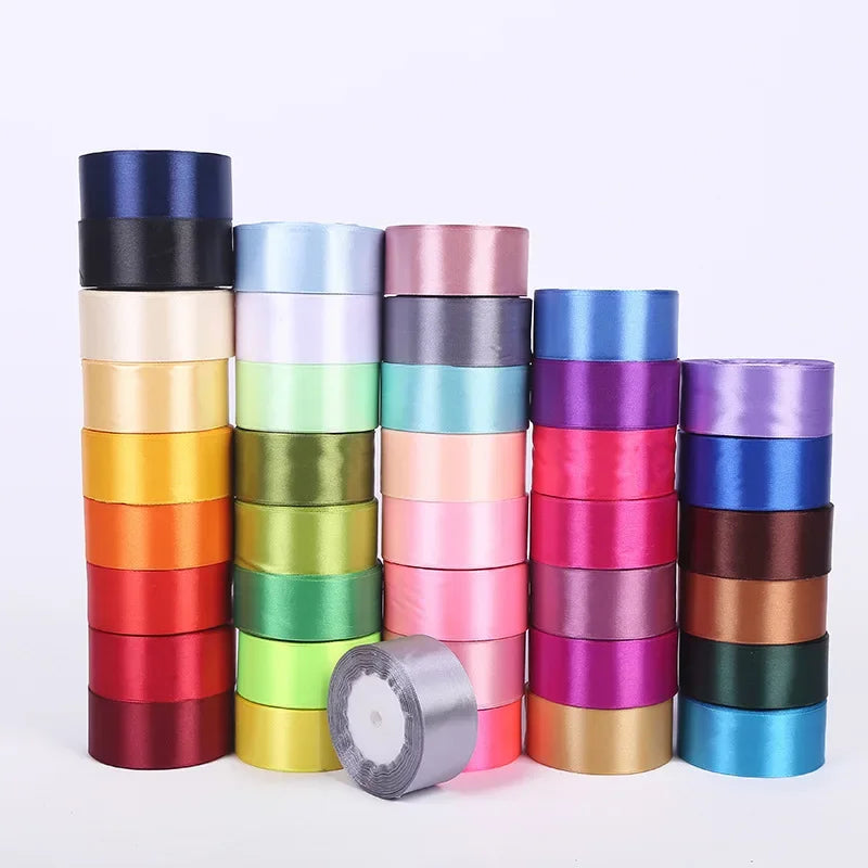 A collection of rolled silk satin ribbon in various shades including blue, green, pink, and gold.