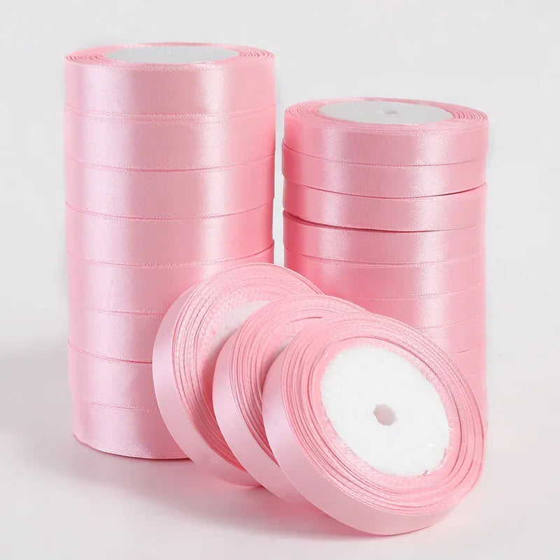 Several rolls of pink silk satin ribbons stacked vertically and horizontally for crafting