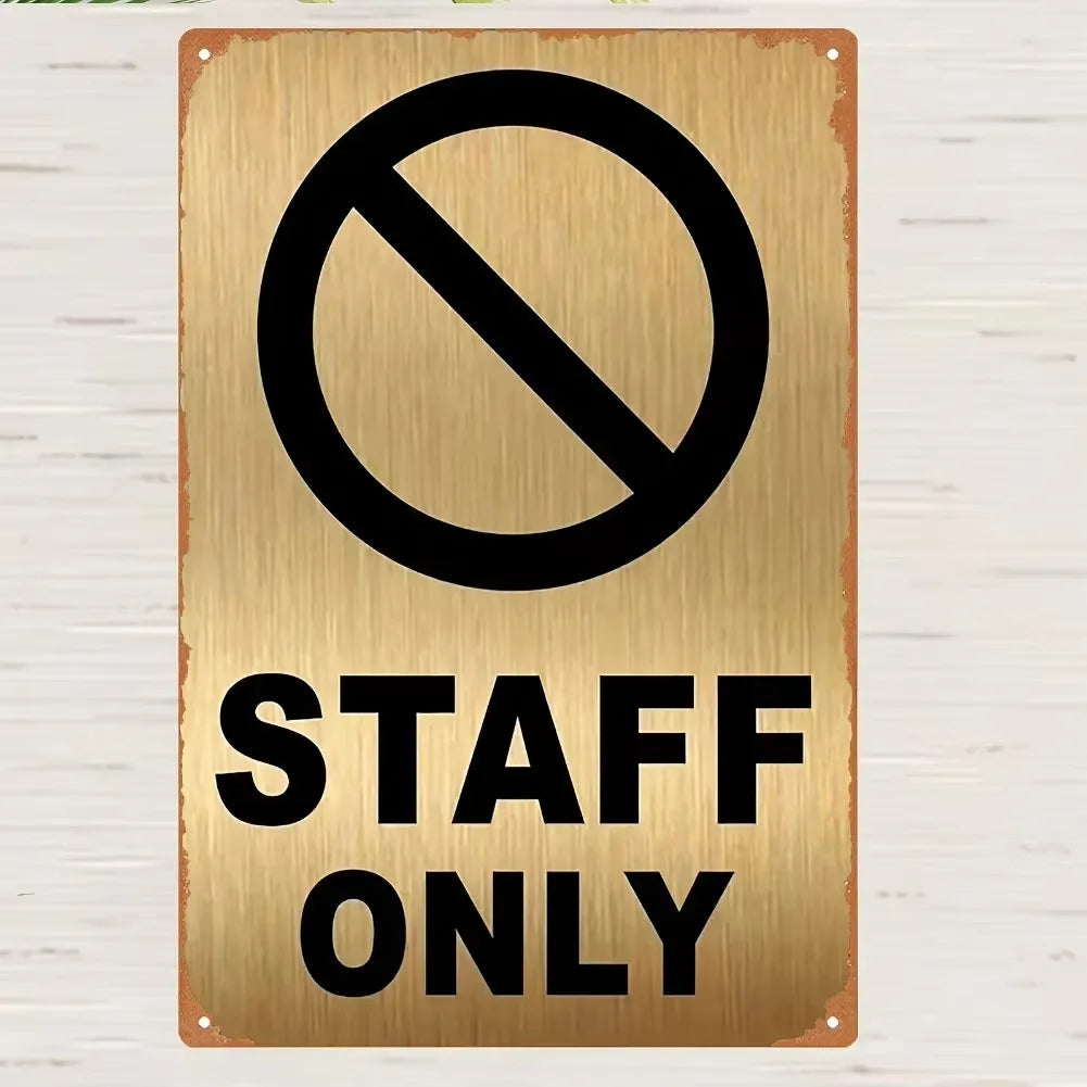 A vintage brass metal sign with a black circle and diagonal line indicating no staff only access.