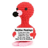 A red crocheted flamingo doll with a pink beak and a card that reads Positive Flamingo