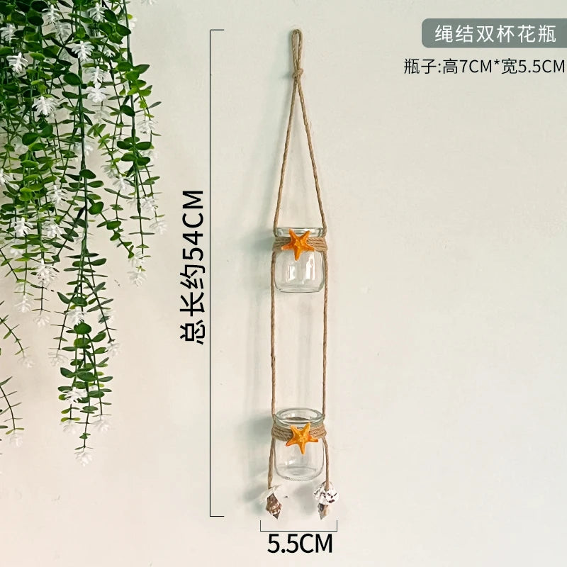 A hanging decorative glass terrarium with a natural twine hanger and an orange starfish decoration.