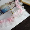 Pink sheer lace trim with delicate bows and gold accents displayed on a white card.
