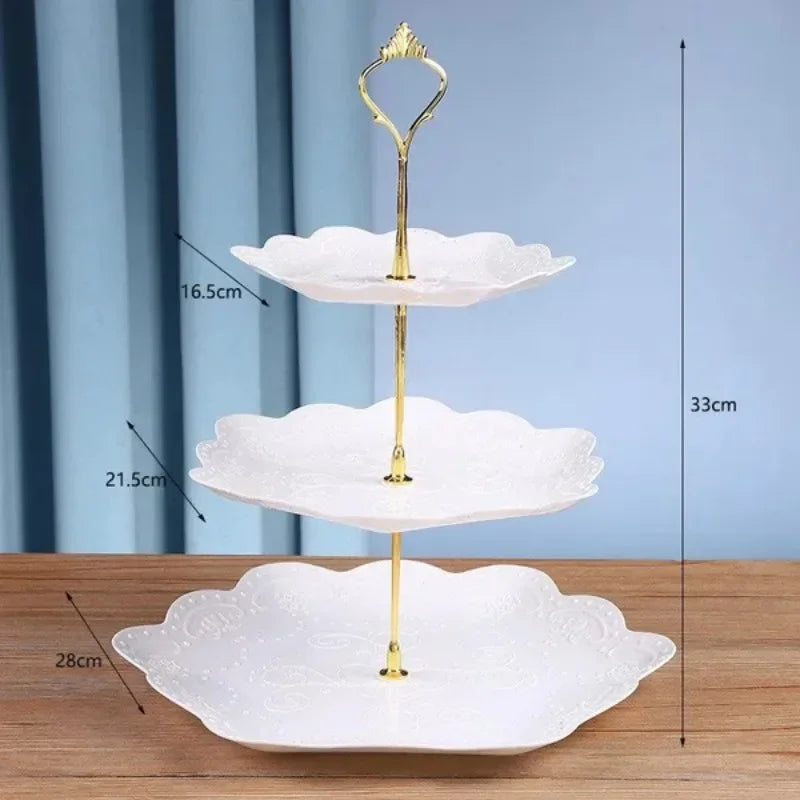 A three-tier gold cake stand with white ceramic plates for serving desserts and fruit.