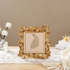 A golden 3D daisy resin photo frame with a natural green leaf inside, displayed on a white lace cloth.