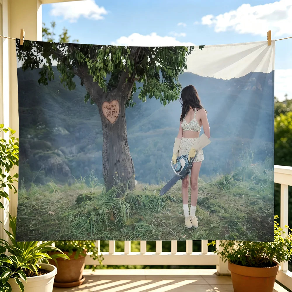 A woman in a white top stands in front of a large tree with a heart carved into its trunk, displayed on a fabric tapestry.