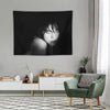 A black and white portrait of Billie Eilish as a tapestry wall hanging displayed on a light gray wall.