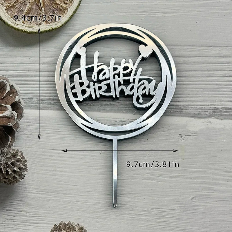 Silver acrylic birthday cake topper featuring the words Happy Birthday on a circular design with a stick.