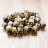 A collection of 20 realistic resin mini skulls used for garden decor, arranged on a light wooden surface.