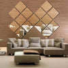 A decorative wall art piece made of four diamond-shaped acrylic mirror stickers mounted on a wooden background.