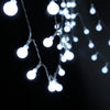A close-up shot of a string of white globe LED lights hanging against a dark background.