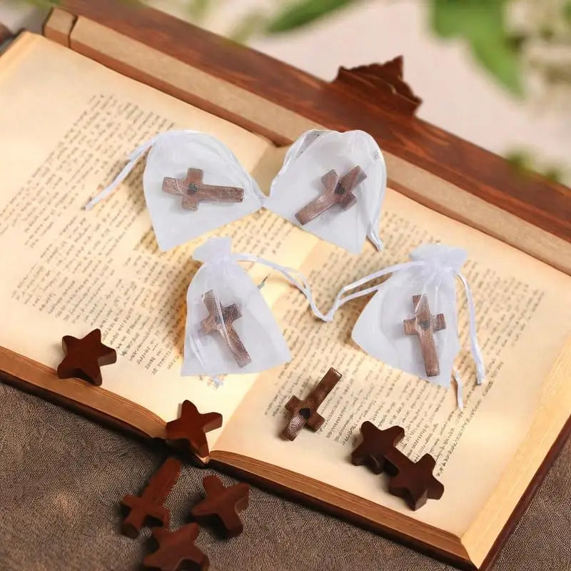 Several small wooden crosses are placed inside white fabric pouches within an open book.