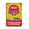 Vintage metal garage sign with red and yellow paint featuring the text NGK Spark Plugs and Optimise Engine Performance