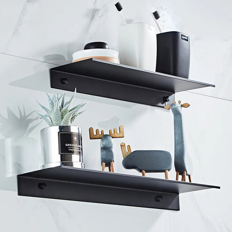 Black floating metal wall shelves displaying various bathroom and kitchen storage items like toothbrushes and plant pots
