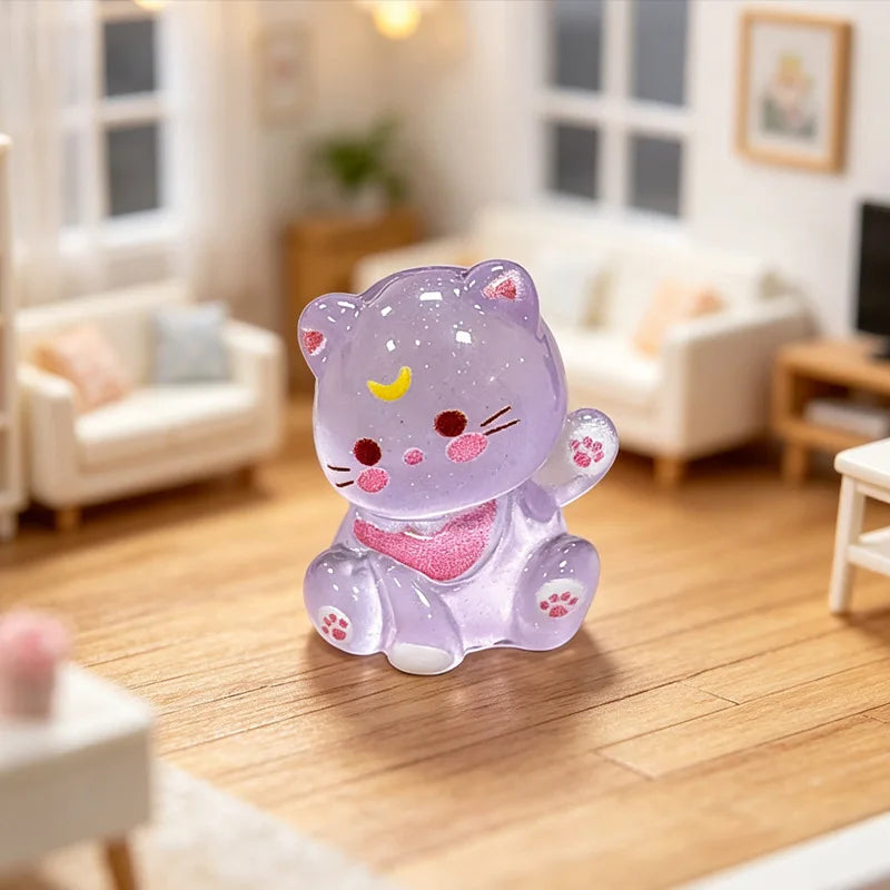 A small, purple resin cat keychain with pink accents sitting on a wooden floor.