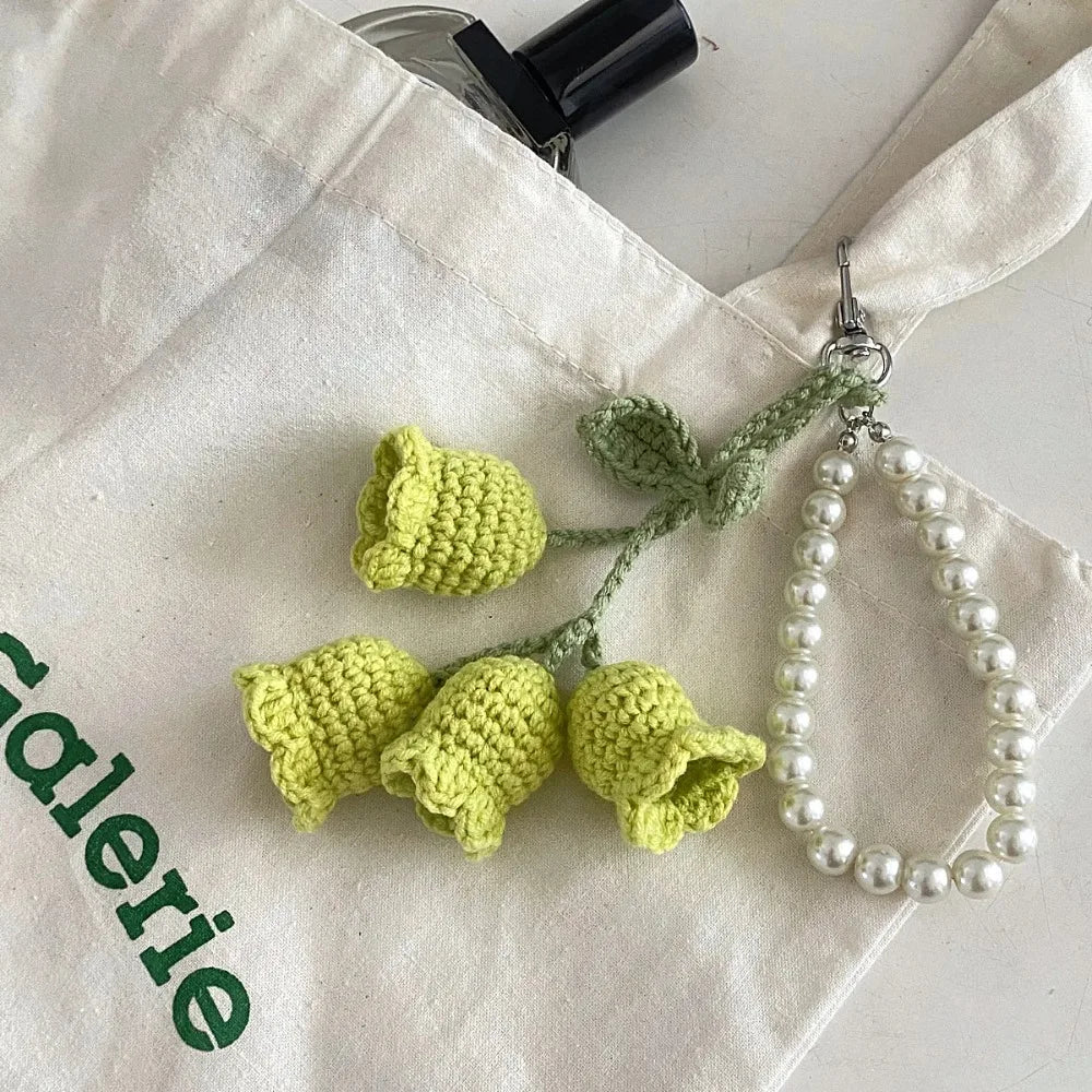 Handmade pearl chain orchid key ring attached to a white fabric background.