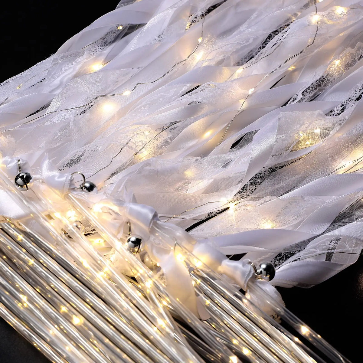 LED glow wands with ribbons and bells draped in sheer white fabric for weddings and parties