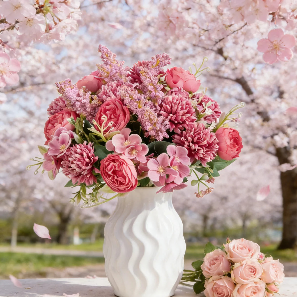 A bouquet of artificial silk peony flowers in shades of pink and magenta arranged in a white vase against a backdrop of cherr