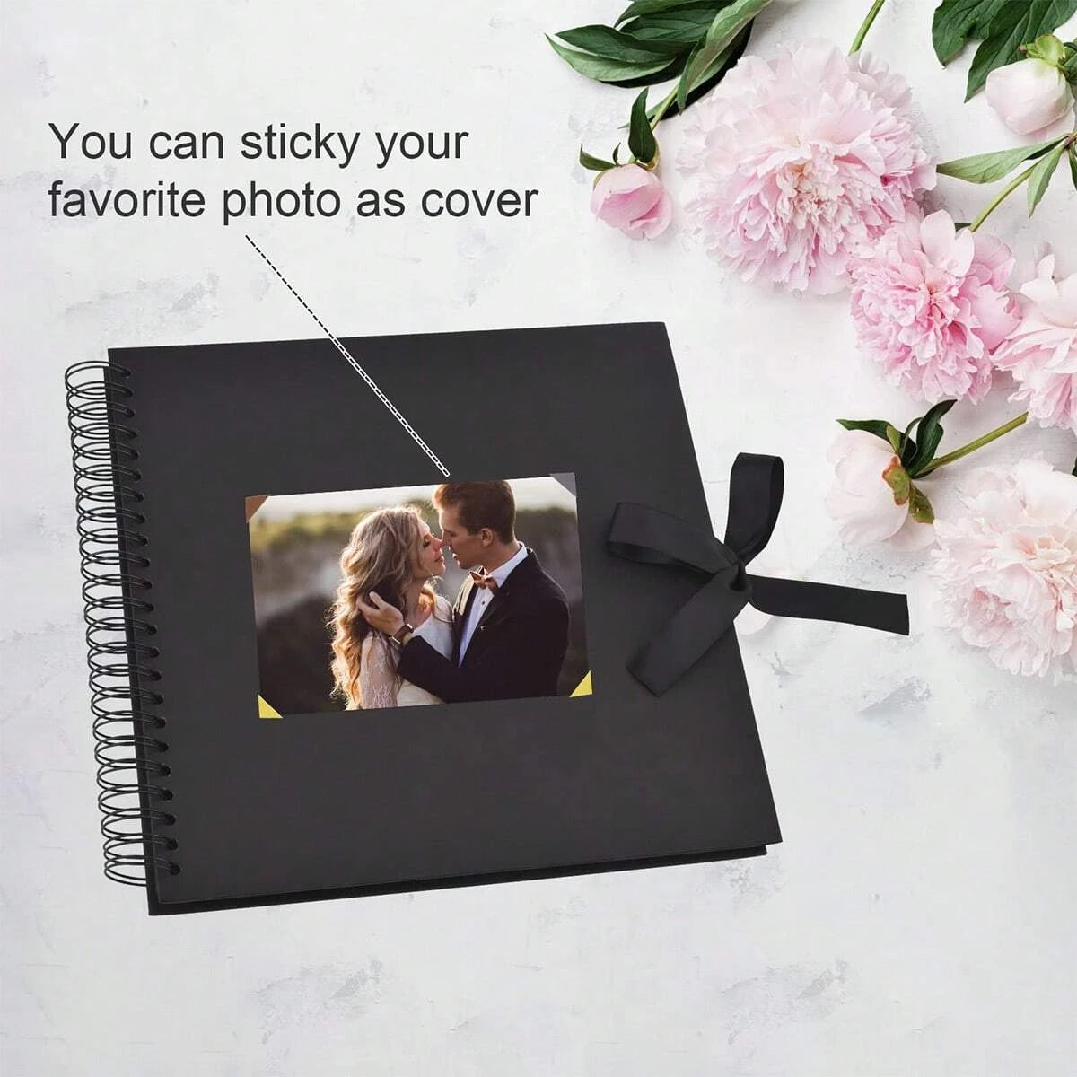Un cuaderno espiral negro con una foto en la portada, rodeado de flores rosas.