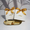Two white thank you gift bags tied with gold ribbon resting on a gold tray.