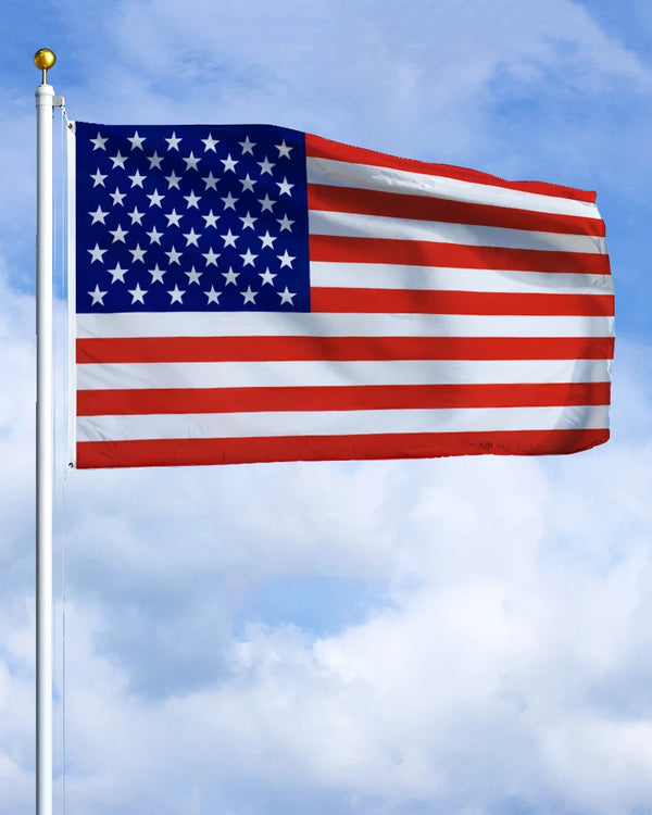 A large American flag waving on a flagpole against a blue sky.
