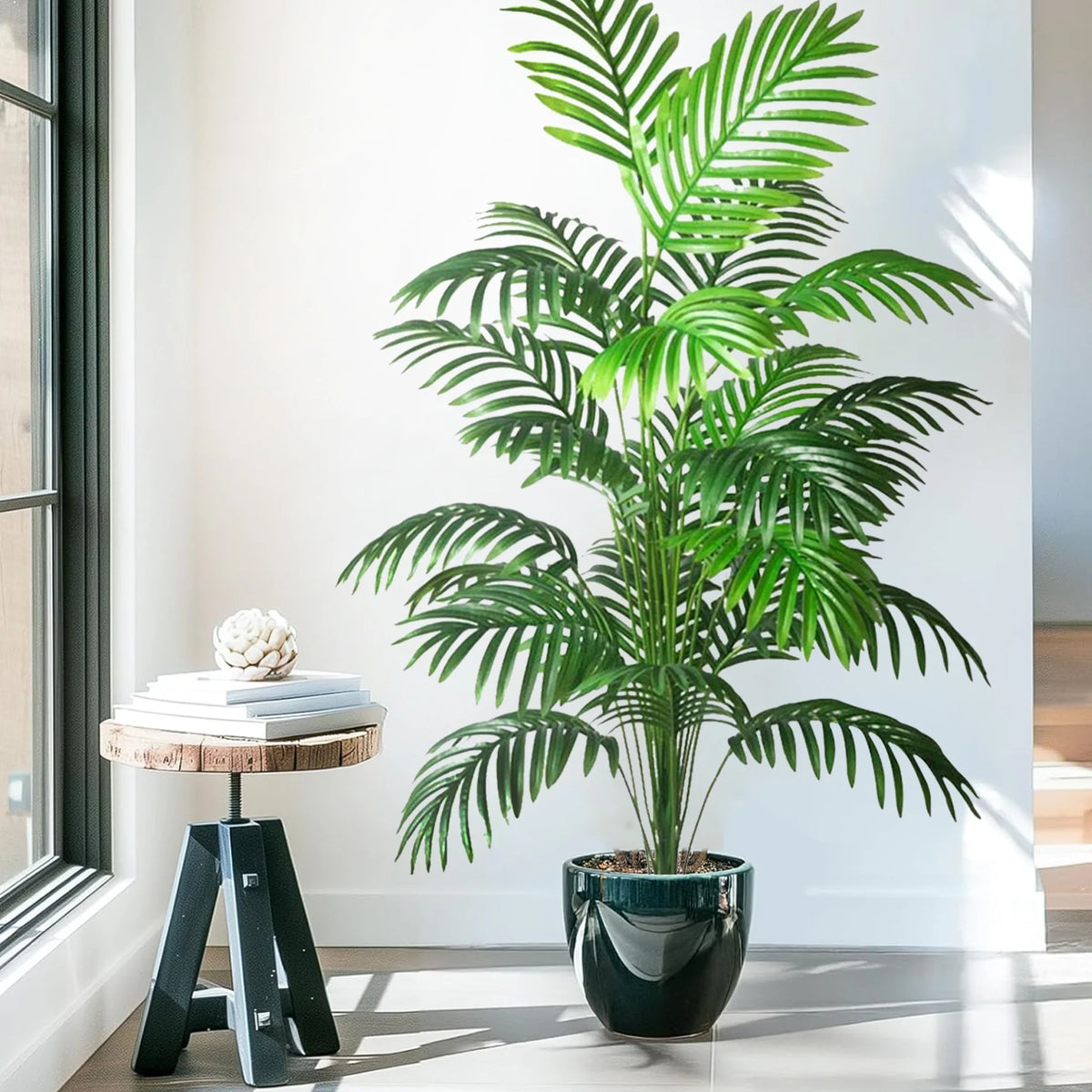 A realistic artificial palm tree with vibrant green silk leaves potted in a dark vase on a white floor.