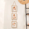 A vertical arrangement of four wooden photo frames with gold accents hanging on a wall next to a macrame wall hanging.