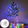 A decorated Christmas tree illuminated with blue and purple fairy string lights on a wooden surface.