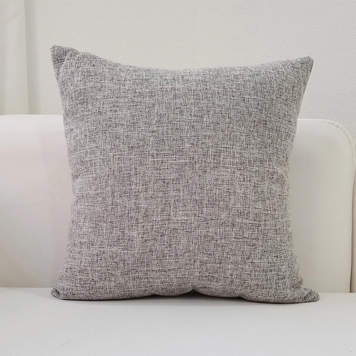 A gray linen pillow is displayed on a white surface.