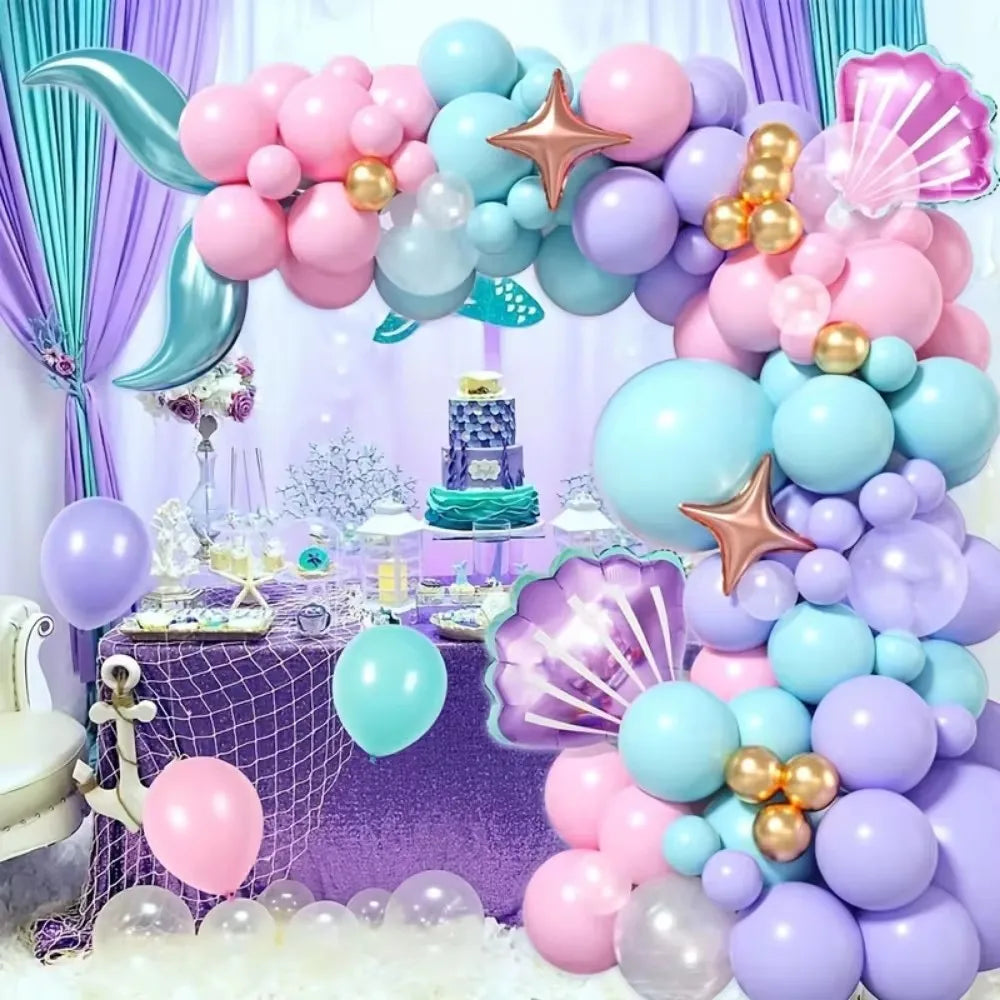 A balloon garland arch set featuring shades of purple, pink, and blue balloons with a mermaid theme.