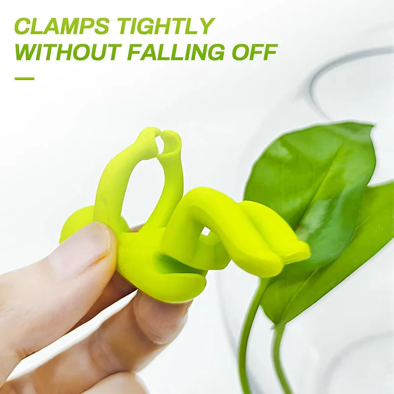 A hand holds a bright lime green, human-shaped plant clamp designed for supporting hydroponic growth.