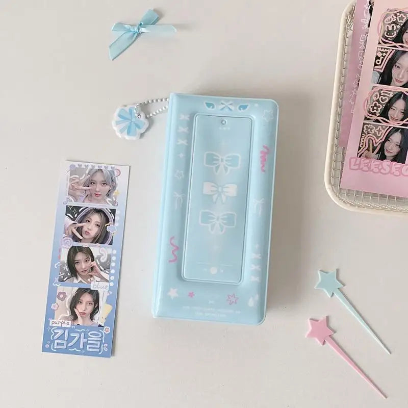 Un álbum de cabina de fotos azul claro con un lazo decorativo y detalles rosas, junto a varias tarjetas de fotos.